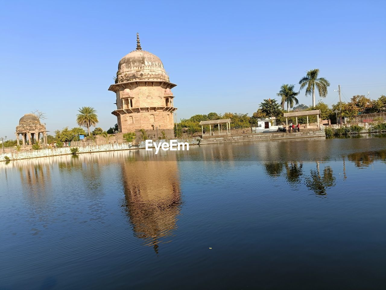 architecture, water, reflection, built structure, travel destinations, building exterior, sky, travel, nature, dome, religion, history, tourism, clear sky, tree, the past, blue, building, plant, place of worship, belief, no people, lake, landmark, city, outdoors, spirituality, day, sunny, ancient, temple - building, palm tree