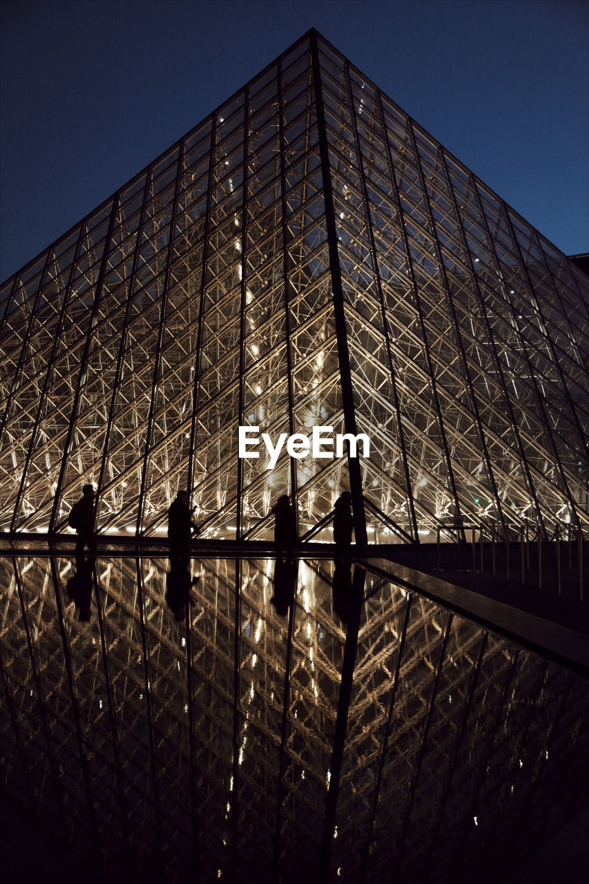 LOW ANGLE VIEW OF ILLUMINATED BUILDING AGAINST CLEAR SKY AT NIGHT