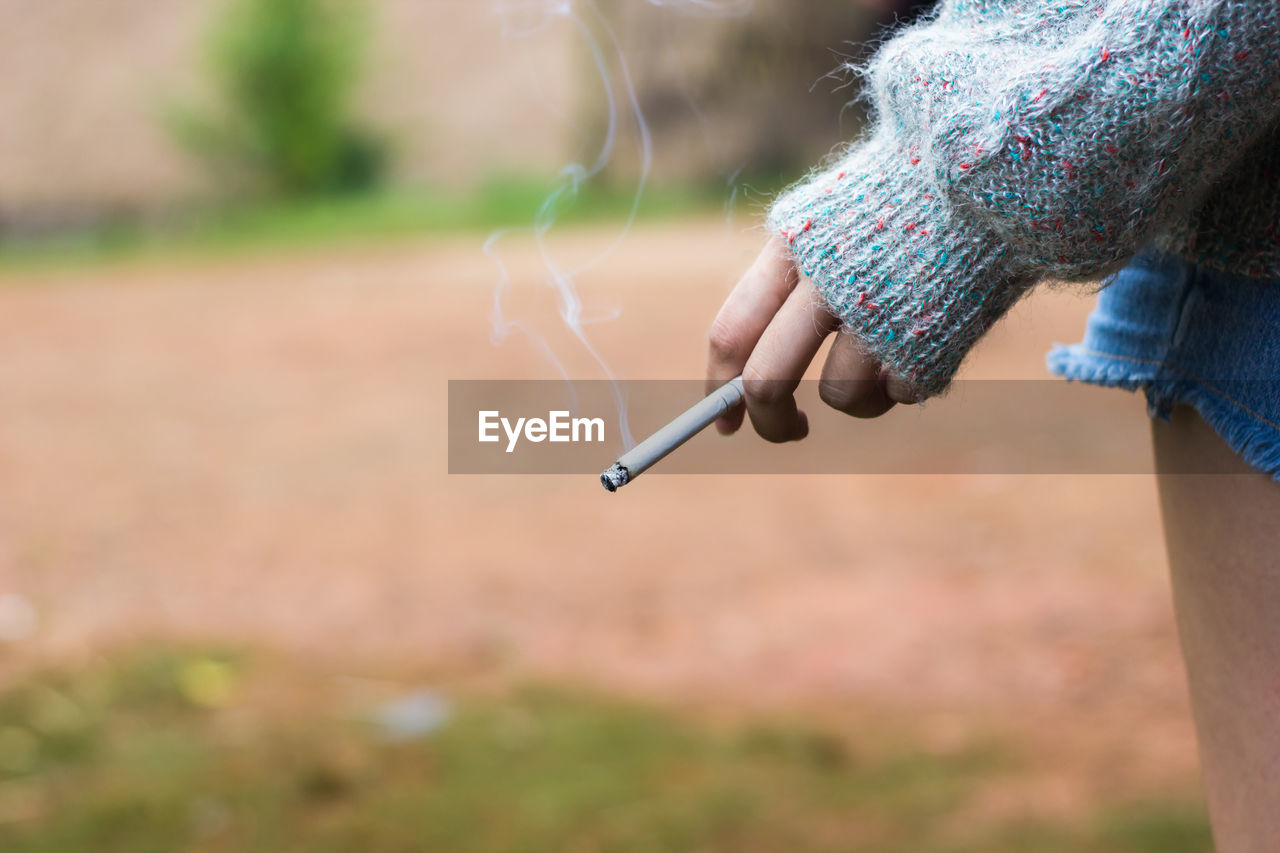 Cropped image of woman smoking cigarette outdoors