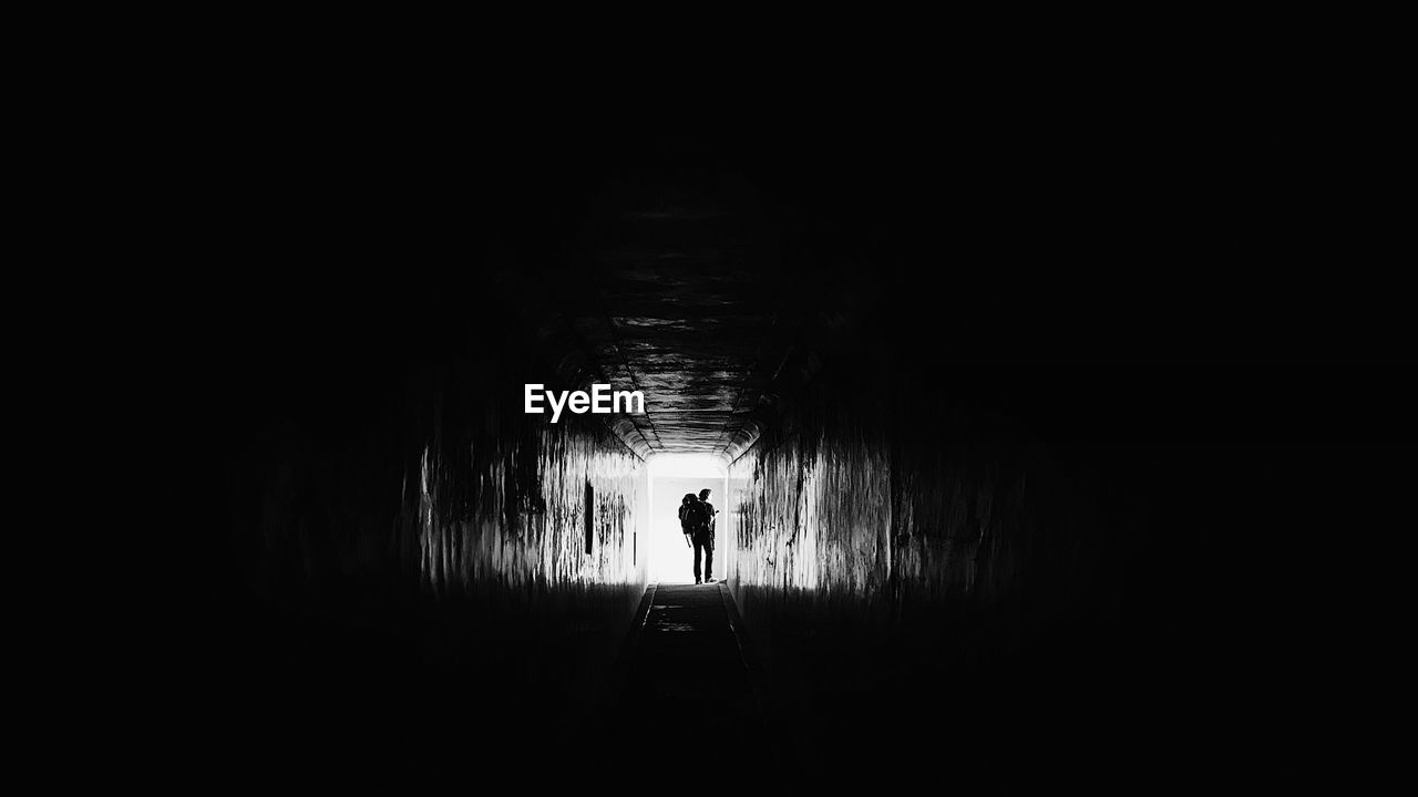 Rear view of silhouette man walking in tunnel