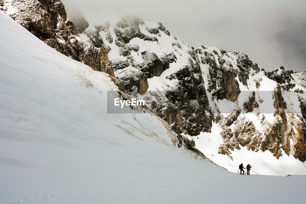 Rear view of men skiing on snowcapped mountain