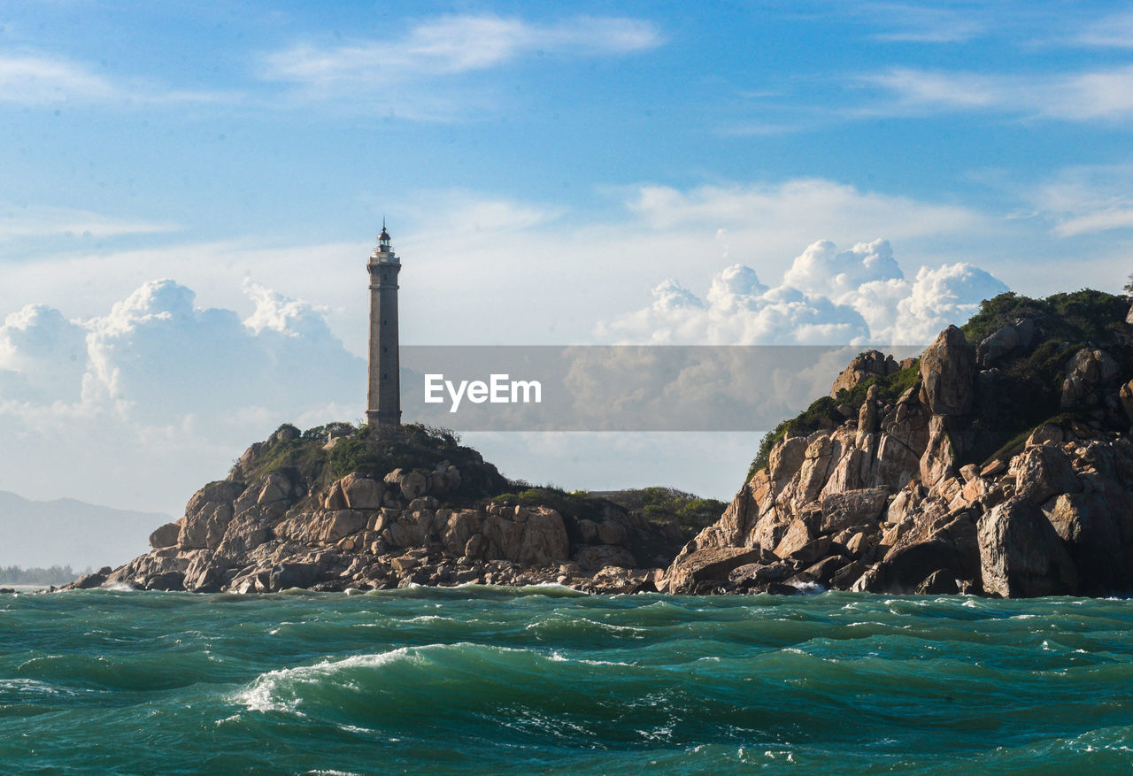 Lighthouse by sea against sky