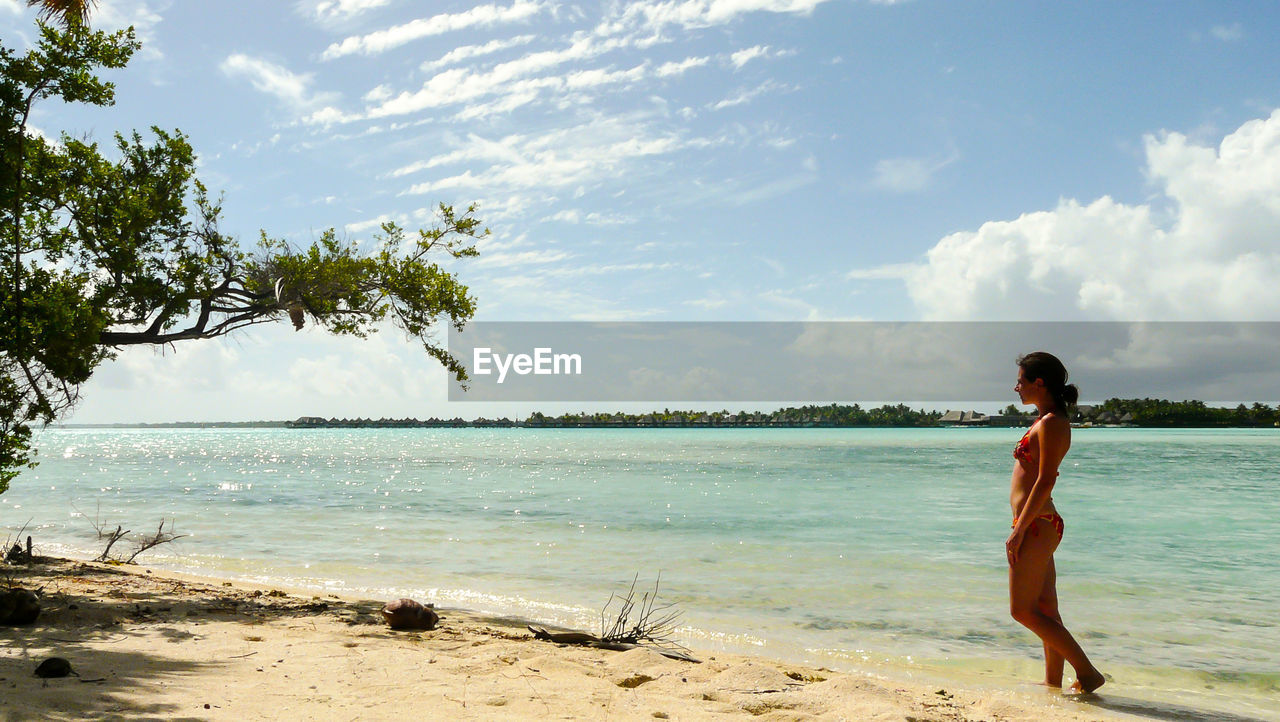 Woman walking at beach against sky