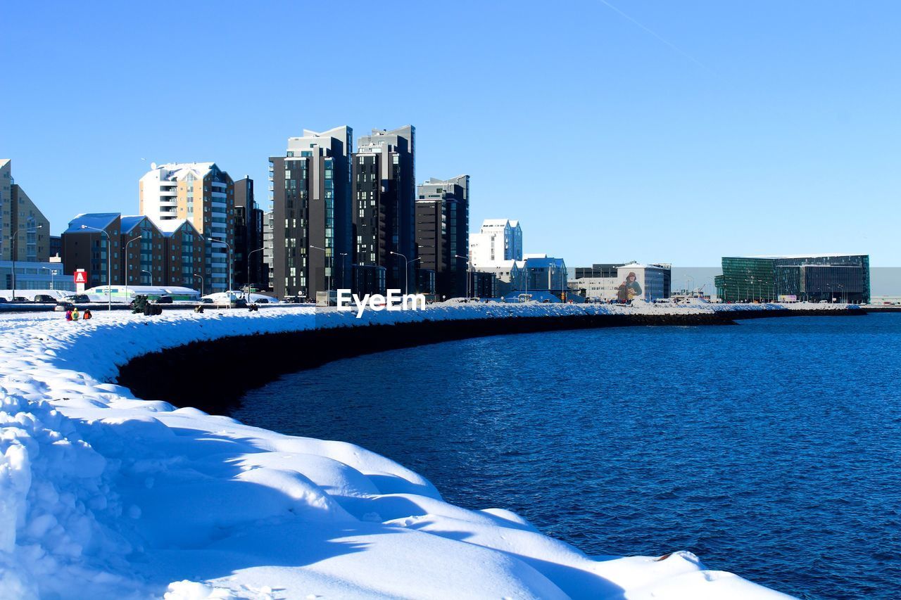 City at waterfront against blue sky