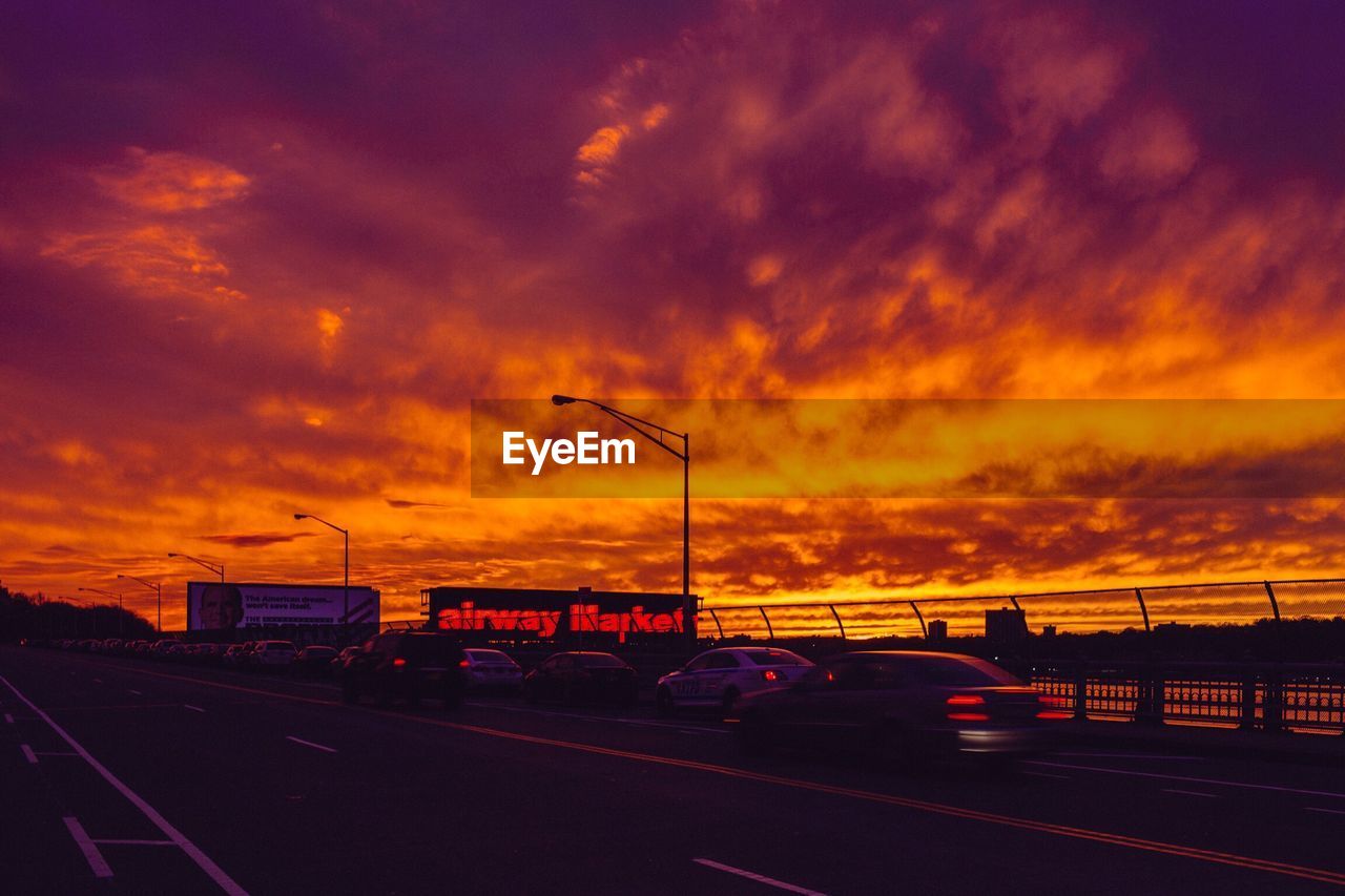 CARS ON ROAD AGAINST DRAMATIC SKY