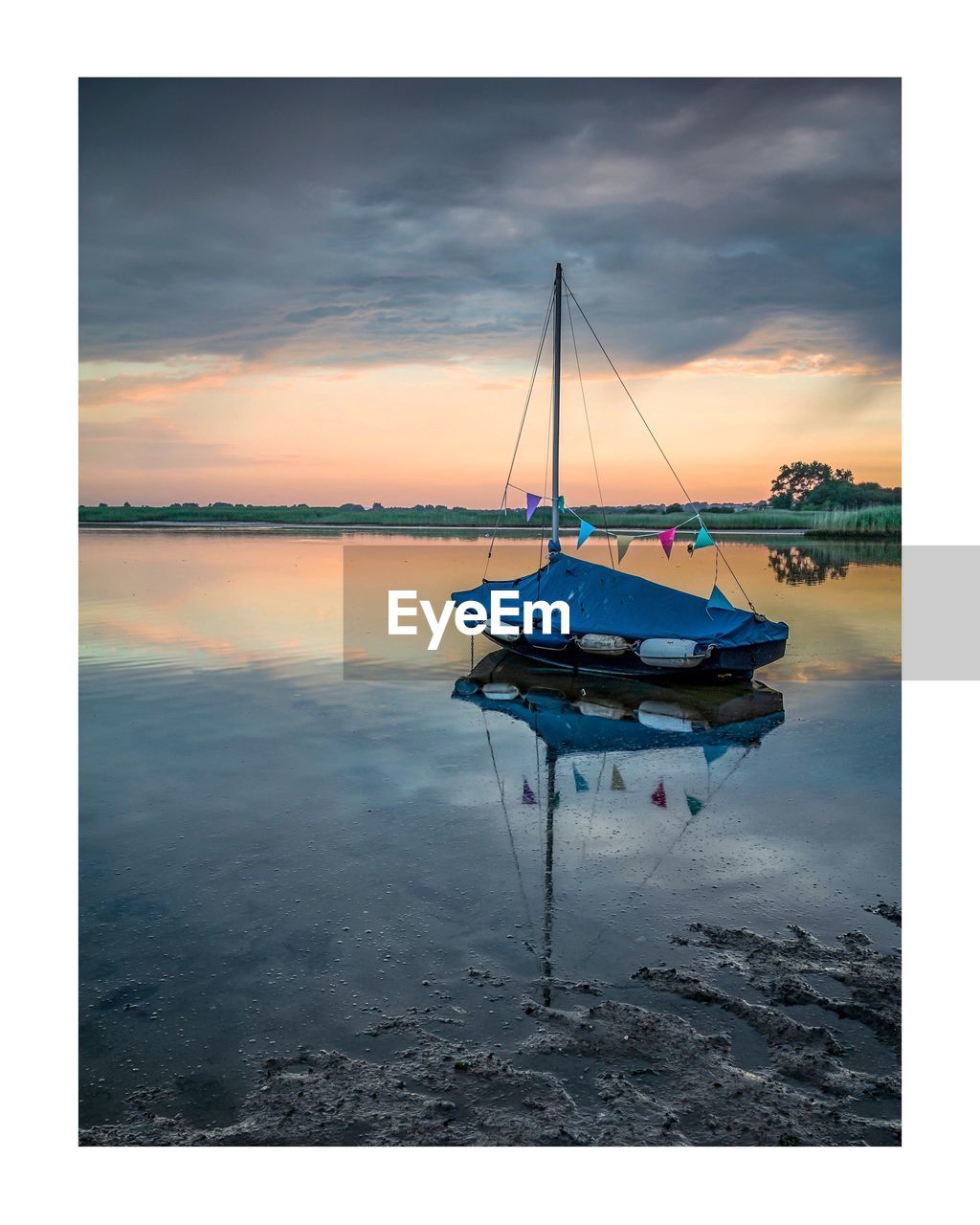 BOATS MOORED IN SEA AT SUNSET