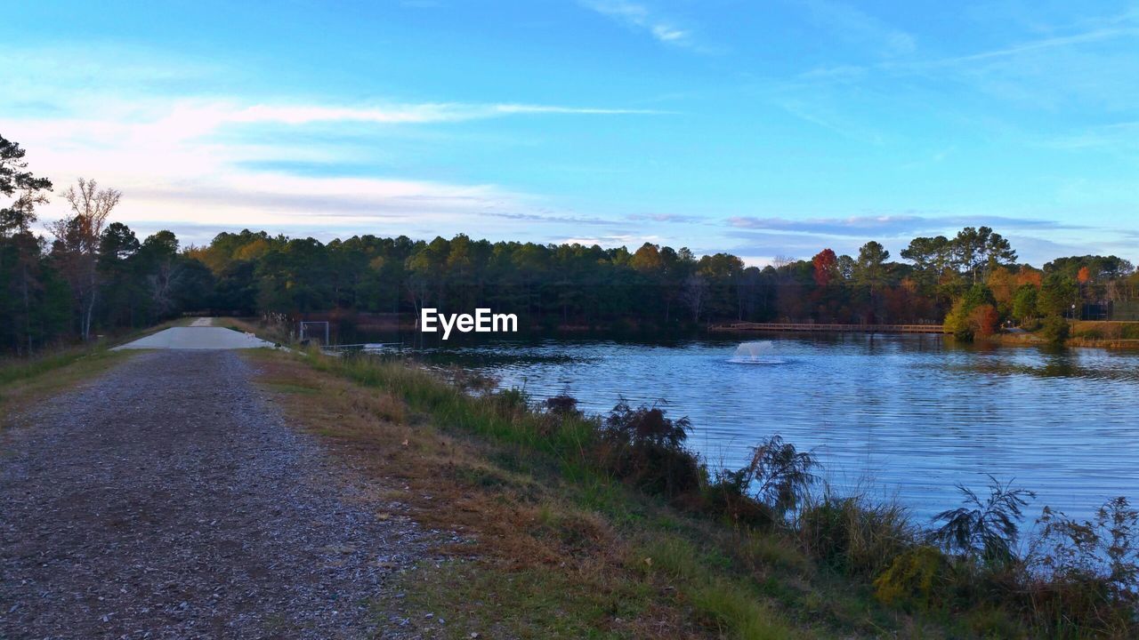 VIEW OF ROAD BY LAKE AGAINST SKY