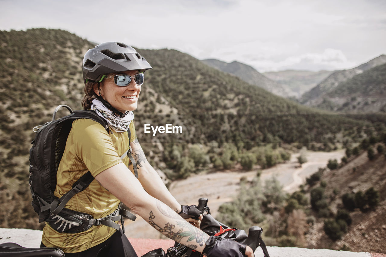 Female cyclist smiles while biking thru the atlas mountains, morocco