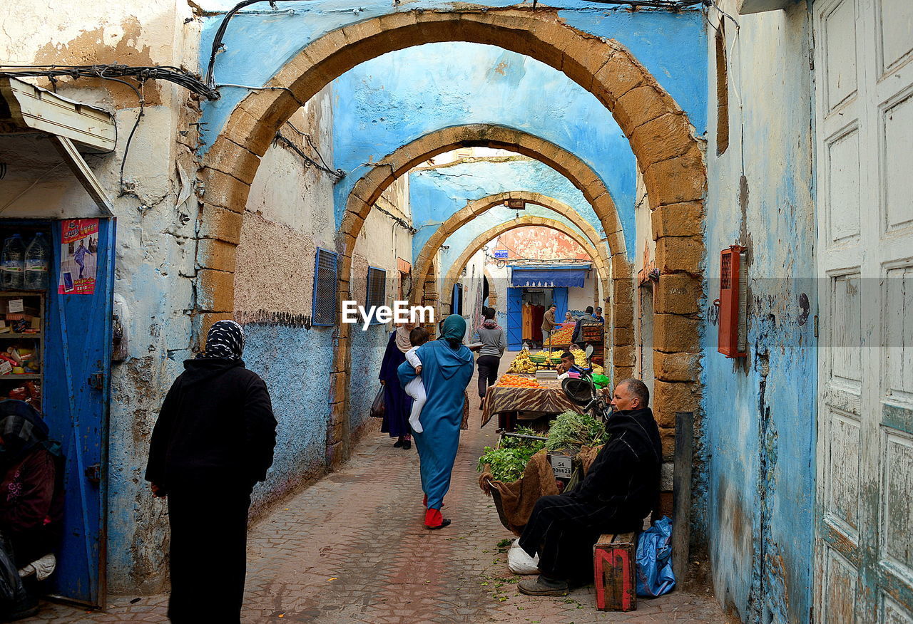 People in market amidst buildings