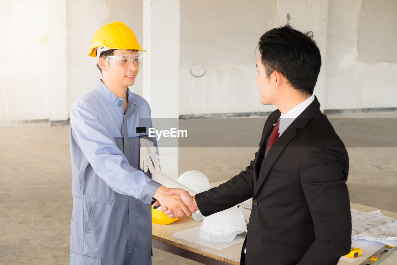 Architects shaking hands at construction site