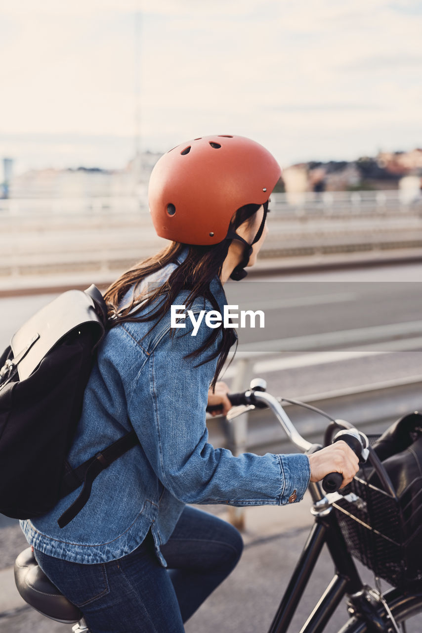 Side view of mid adult woman cycling on bridge