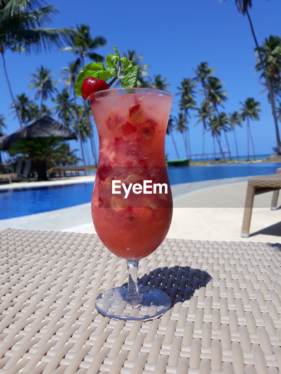 Red drink on table against swimming pool