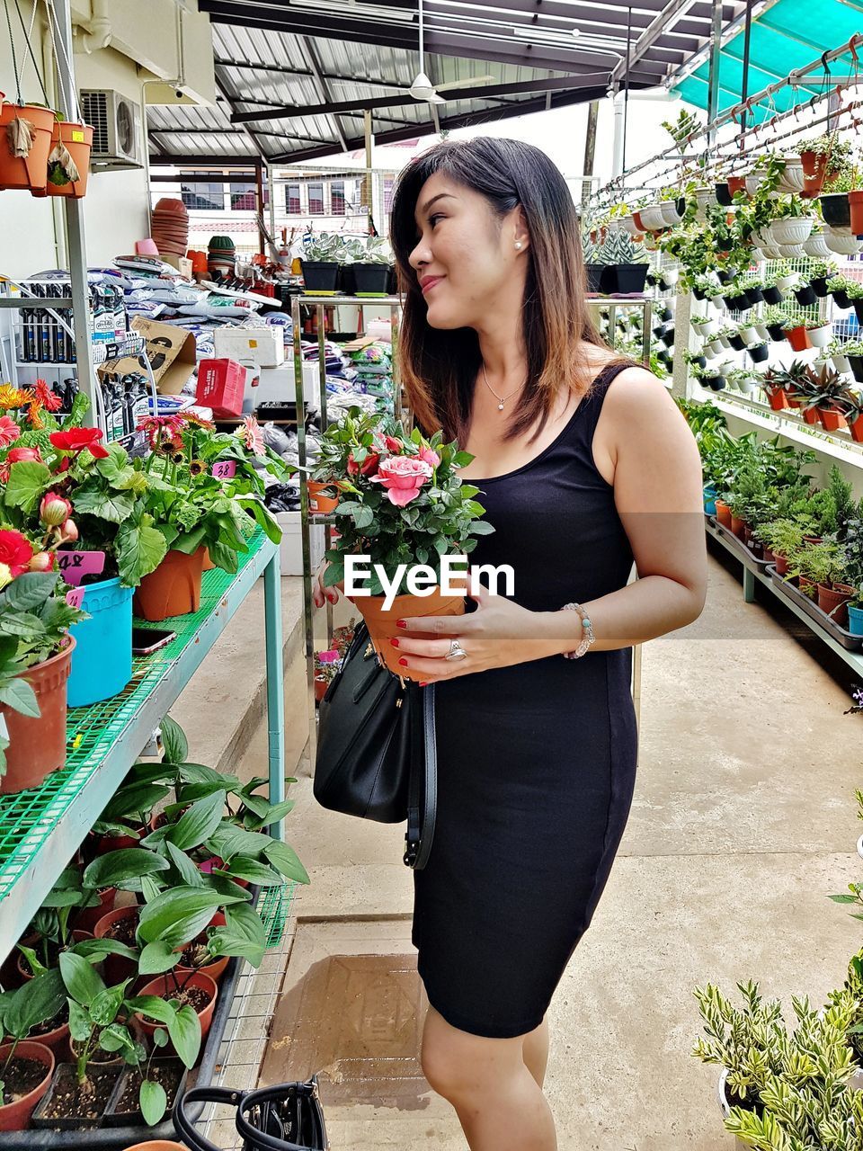 Woman holding potted plant while standing at market stall