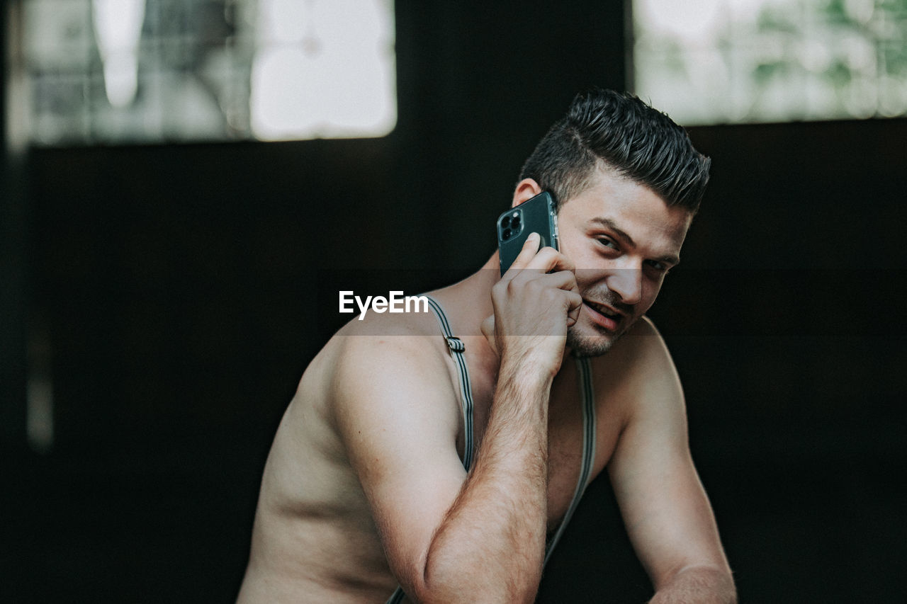 PORTRAIT OF SHIRTLESS YOUNG MAN LOOKING AT HOME