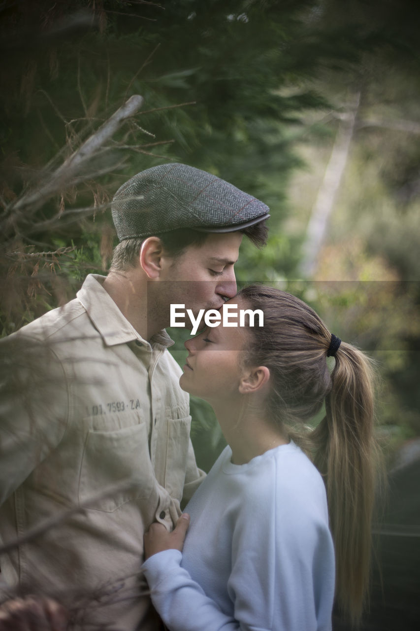 Man kissing girlfriend while standing at park