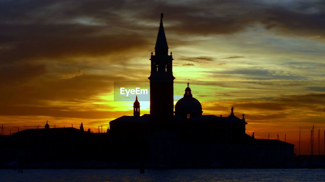 SILHOUETTE OF BUILDING AGAINST ORANGE SKY