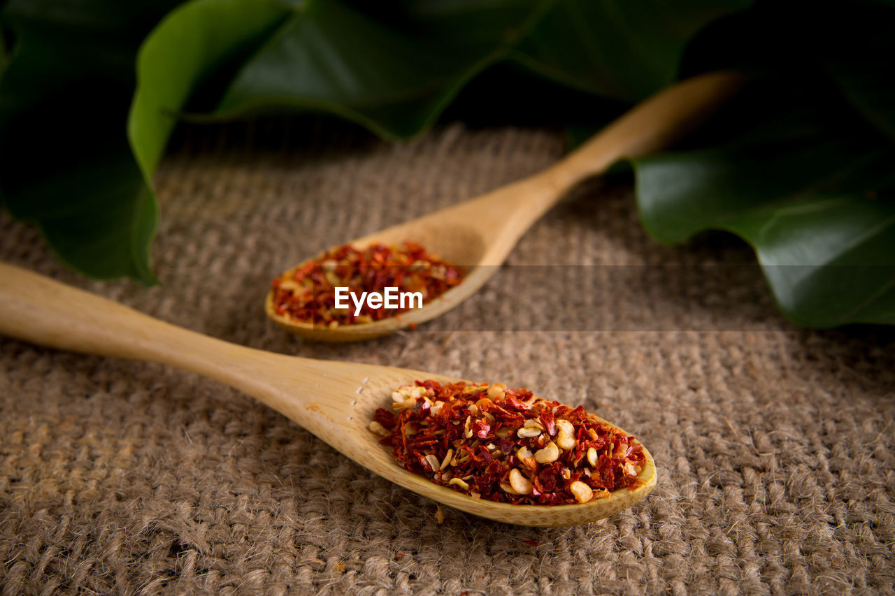 High angle view of dried chili in wooden spoons on burlap