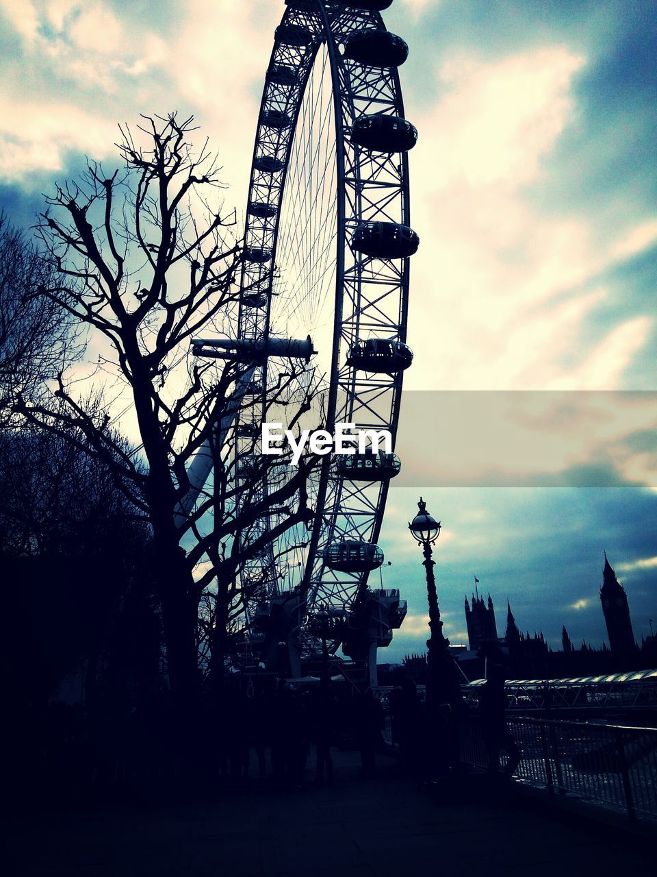 SILHOUETTE OF FERRIS WHEEL AGAINST CLOUDY SKY