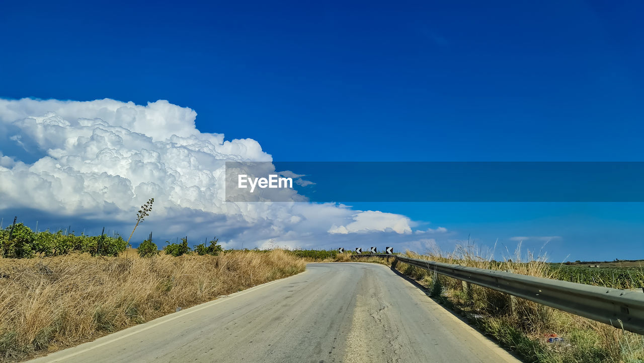 sky, road, transportation, landscape, the way forward, horizon, environment, cloud, highway, blue, nature, scenics - nature, diminishing perspective, land, travel, vanishing point, hill, no people, beauty in nature, plant, country road, field, infrastructure, non-urban scene, day, rural scene, travel destinations, empty road, tranquility, outdoors, tranquil scene, mountain range, road trip, rural area, grass, dirt road, tree, journey, dirt, street, mode of transportation, tourism, remote, copy space, motion, sunlight