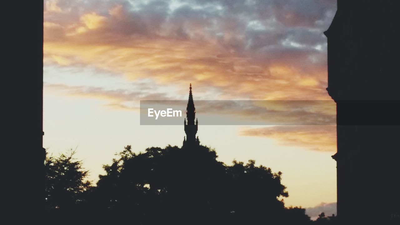 SILHOUETTE OF BUILDING AGAINST CLOUDY SKY