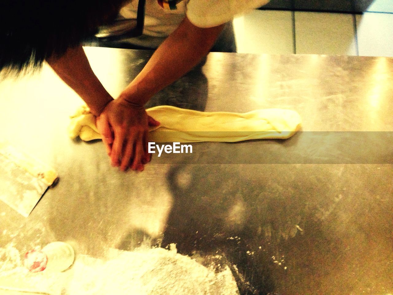 Cropped image of man kneading dough at kitchen