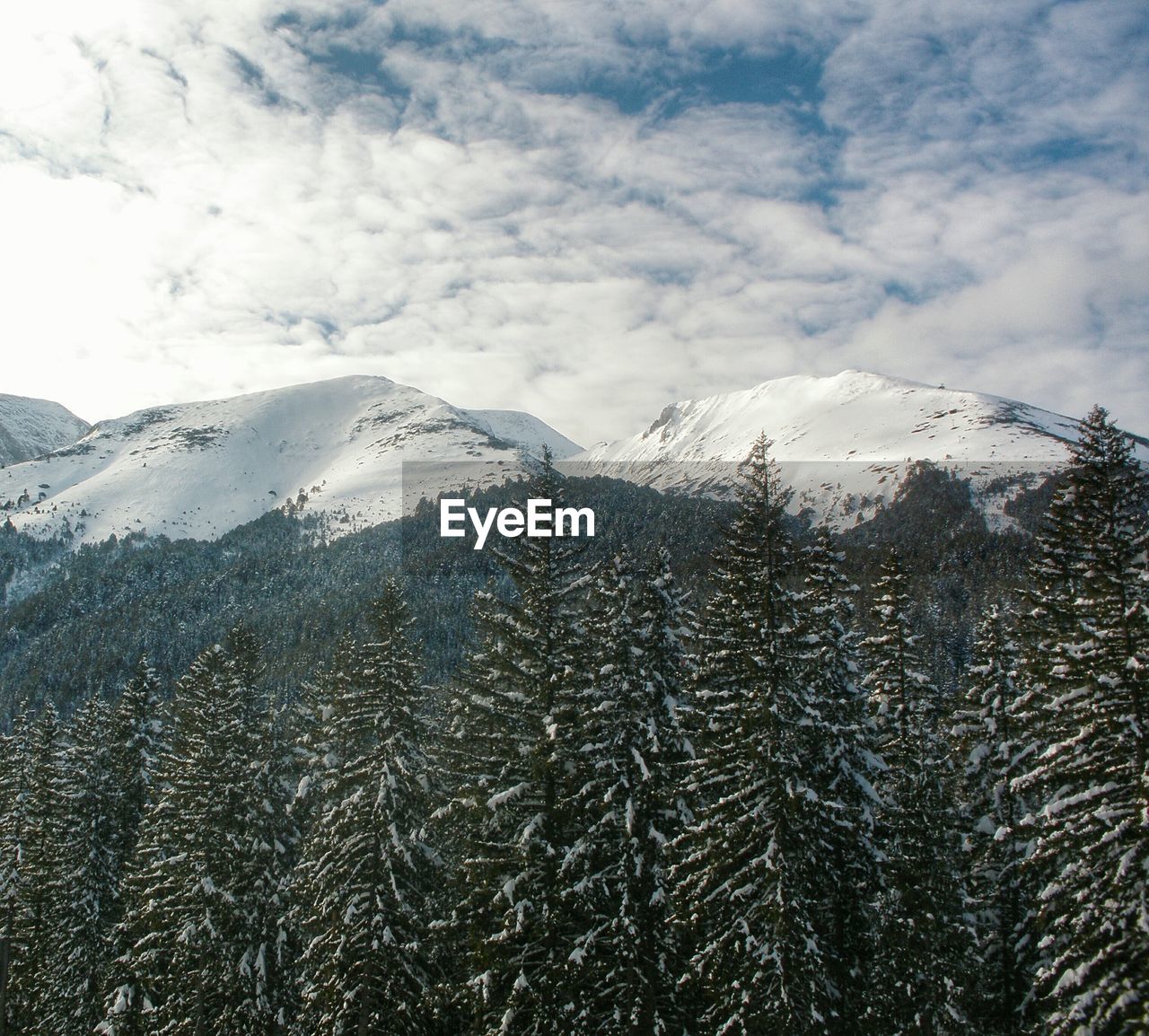 Scenic view of snow covered mountains against cloudy sky