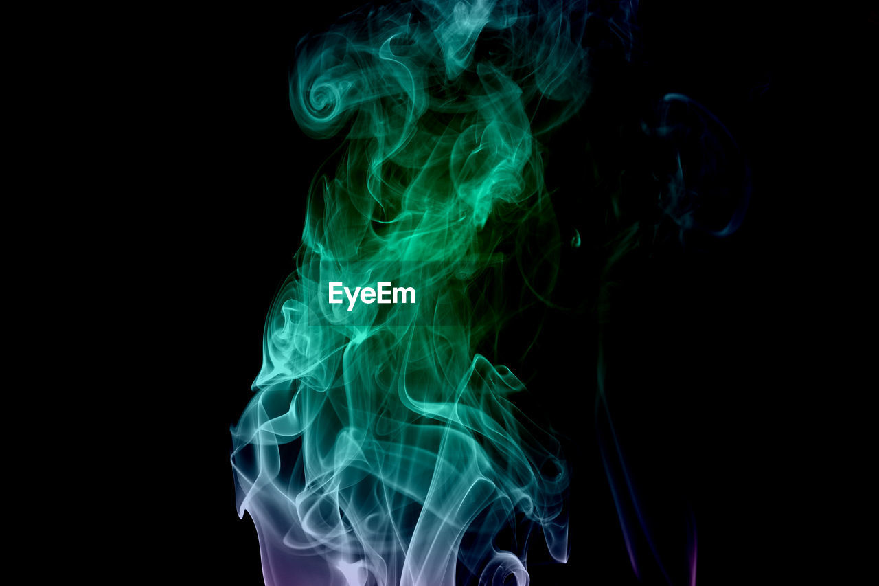 Close-up of illuminated smoke against black background