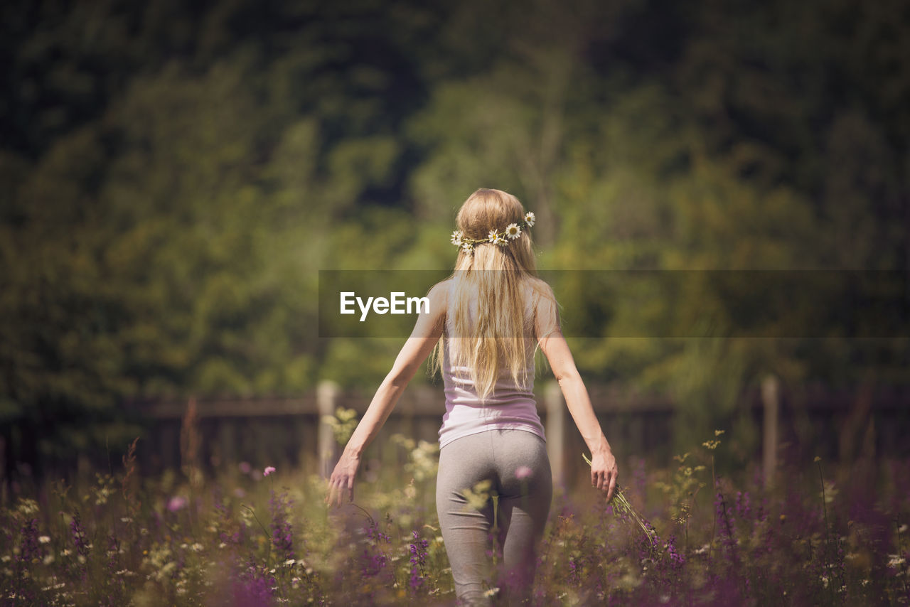 Rear view of woman with headband walking on field during sunny day