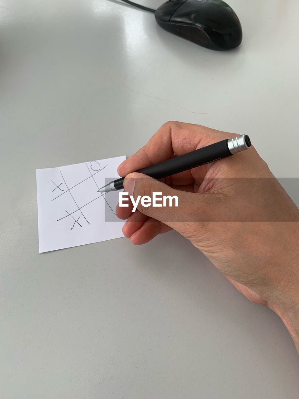 Cropped hand of man writing in paper on table