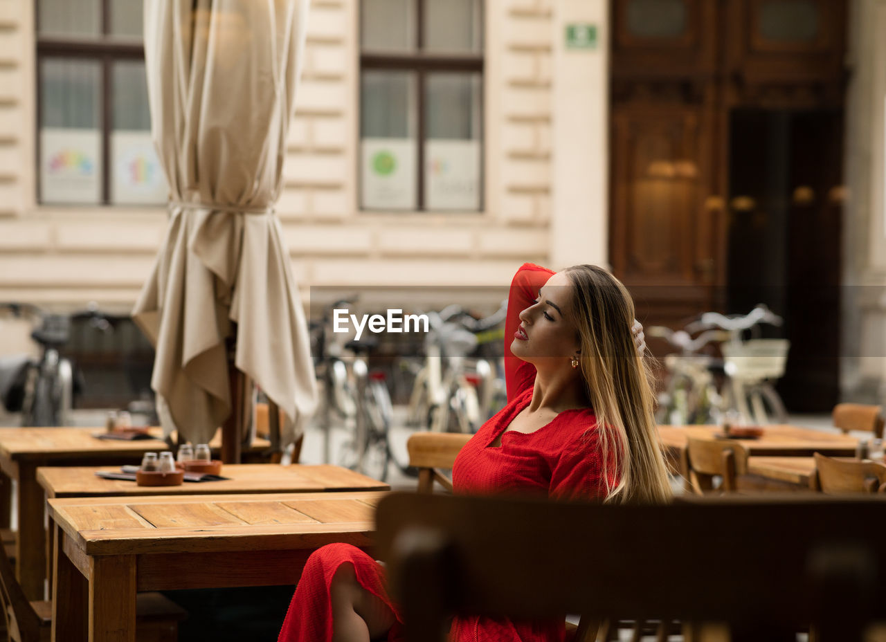 side view of young woman using mobile phone while sitting at table