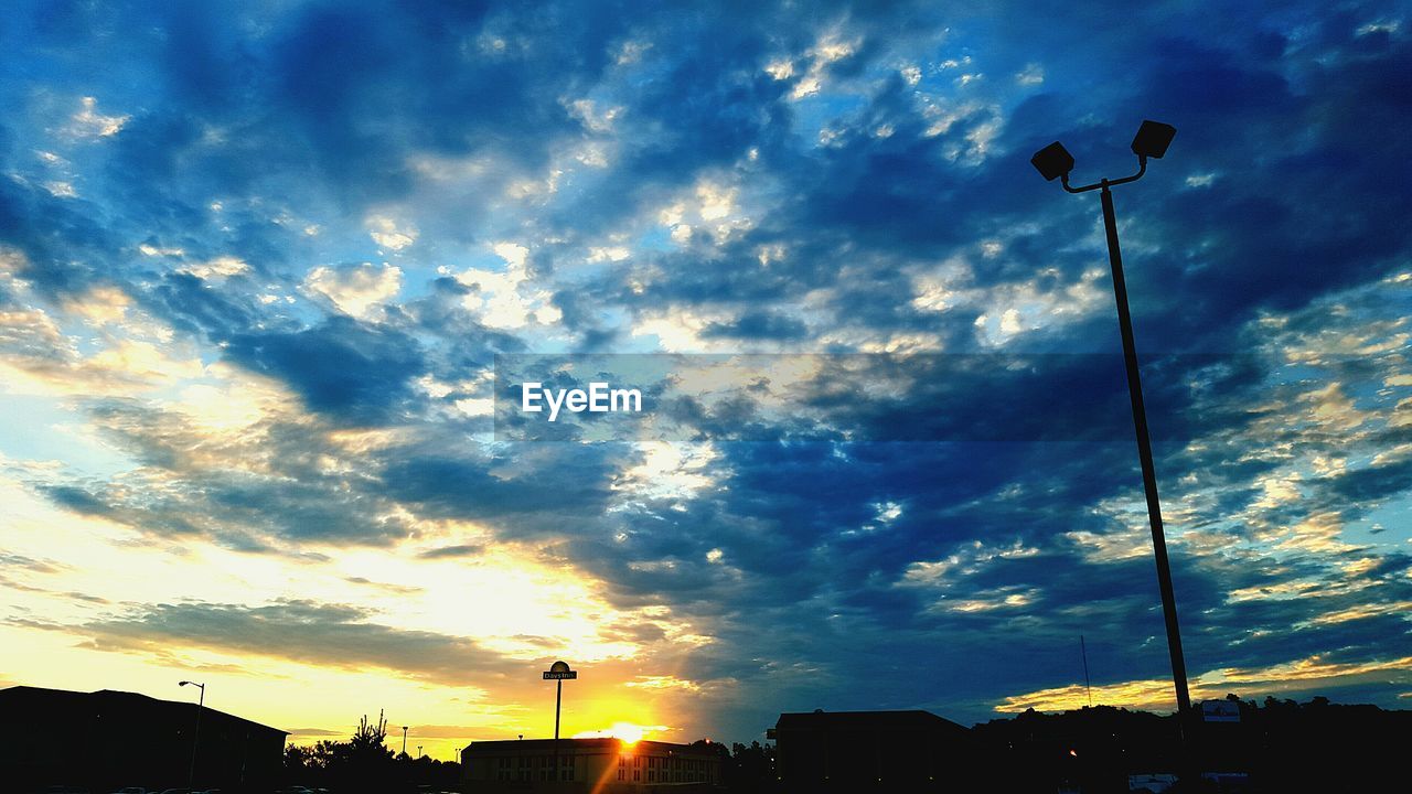 LOW ANGLE VIEW OF STREET LIGHTS AGAINST CLOUDY SKY