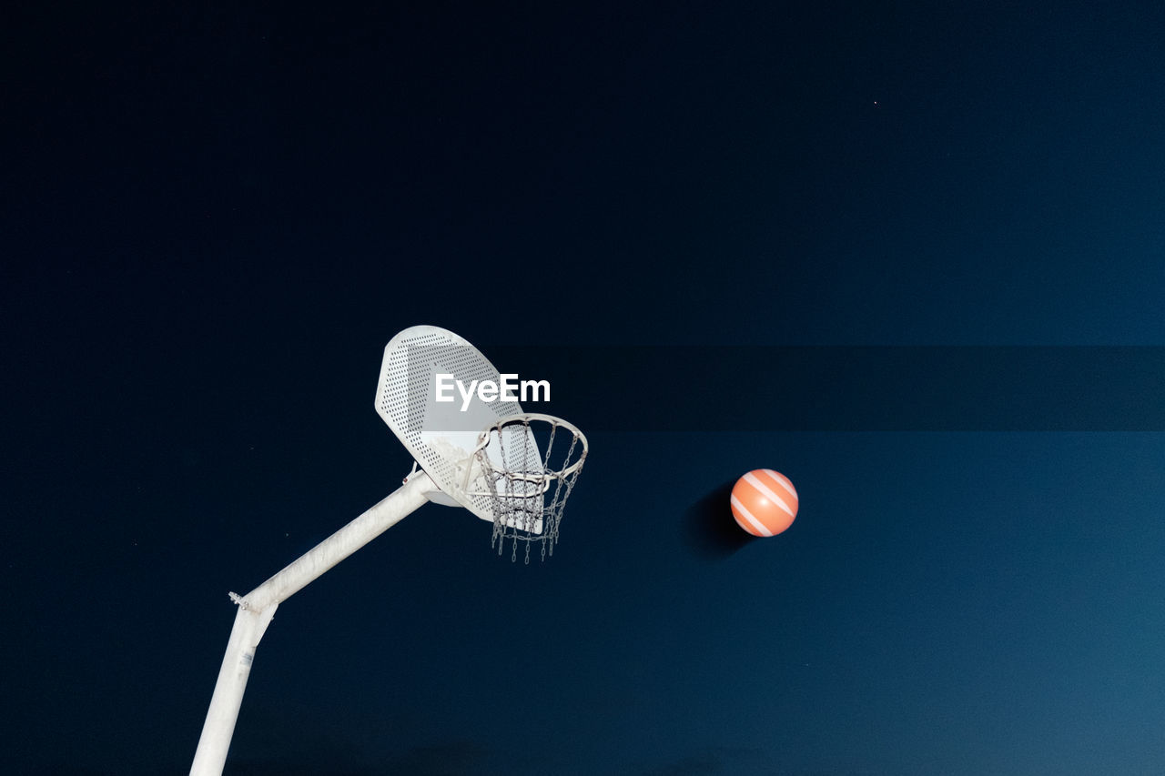 Low angle view of basketball hoop against blue background