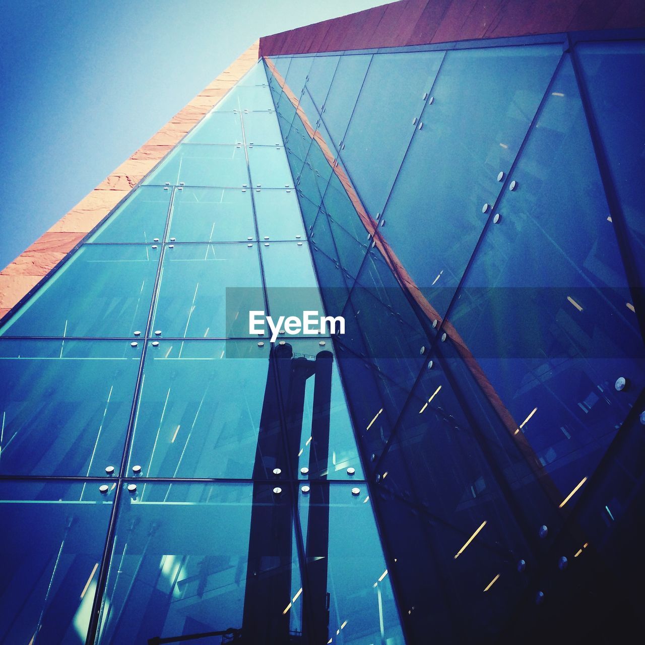 Low angle view of modern glass building against sky