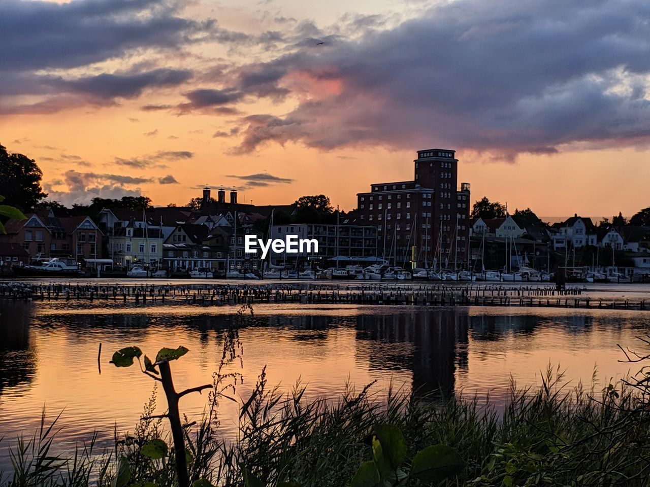 River by buildings against sky during sunset