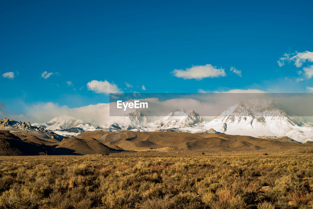 Scenic view of snowcapped mountains against blue sky