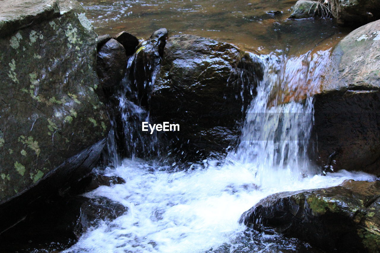 HIGH ANGLE VIEW OF WATERFALL AT RIVERBANK