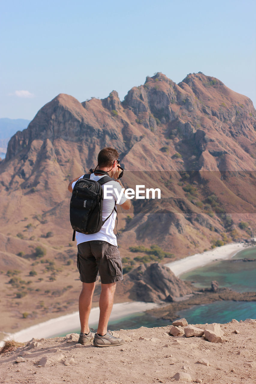 Rear view of man on mountain against sky