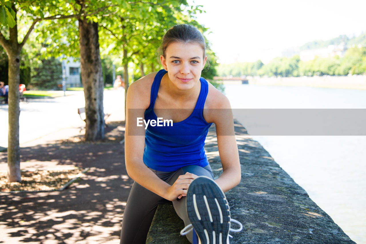 Portrait of teenage girl exercising on retaining wall