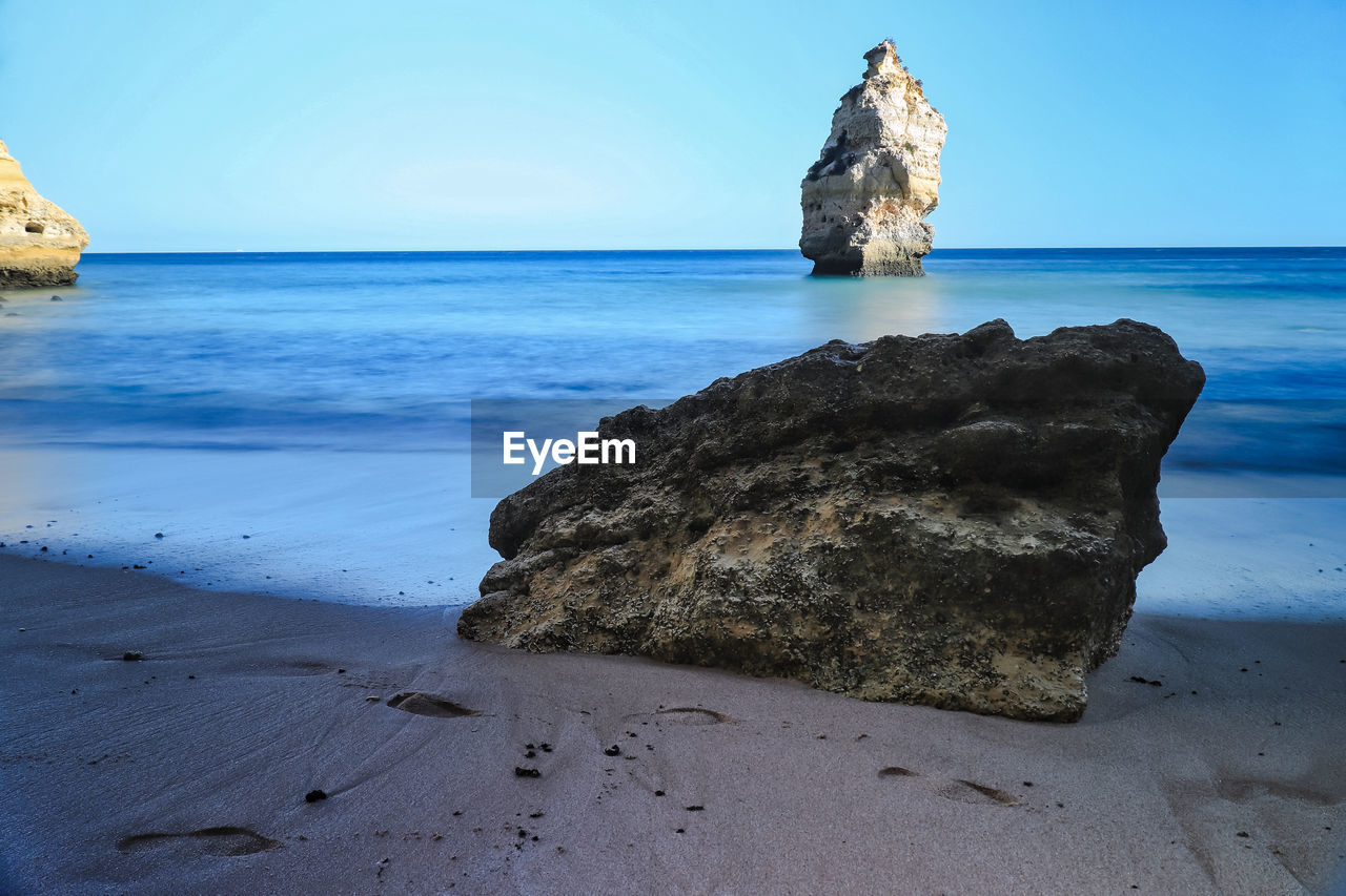 Scenic view of rocks on beach against sky