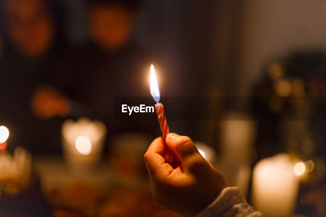 Close-up of hand holding burning candles