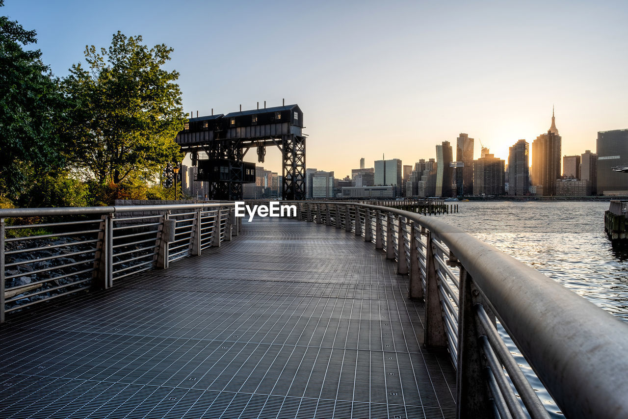 BRIDGE OVER RIVER AMIDST BUILDINGS AGAINST SKY