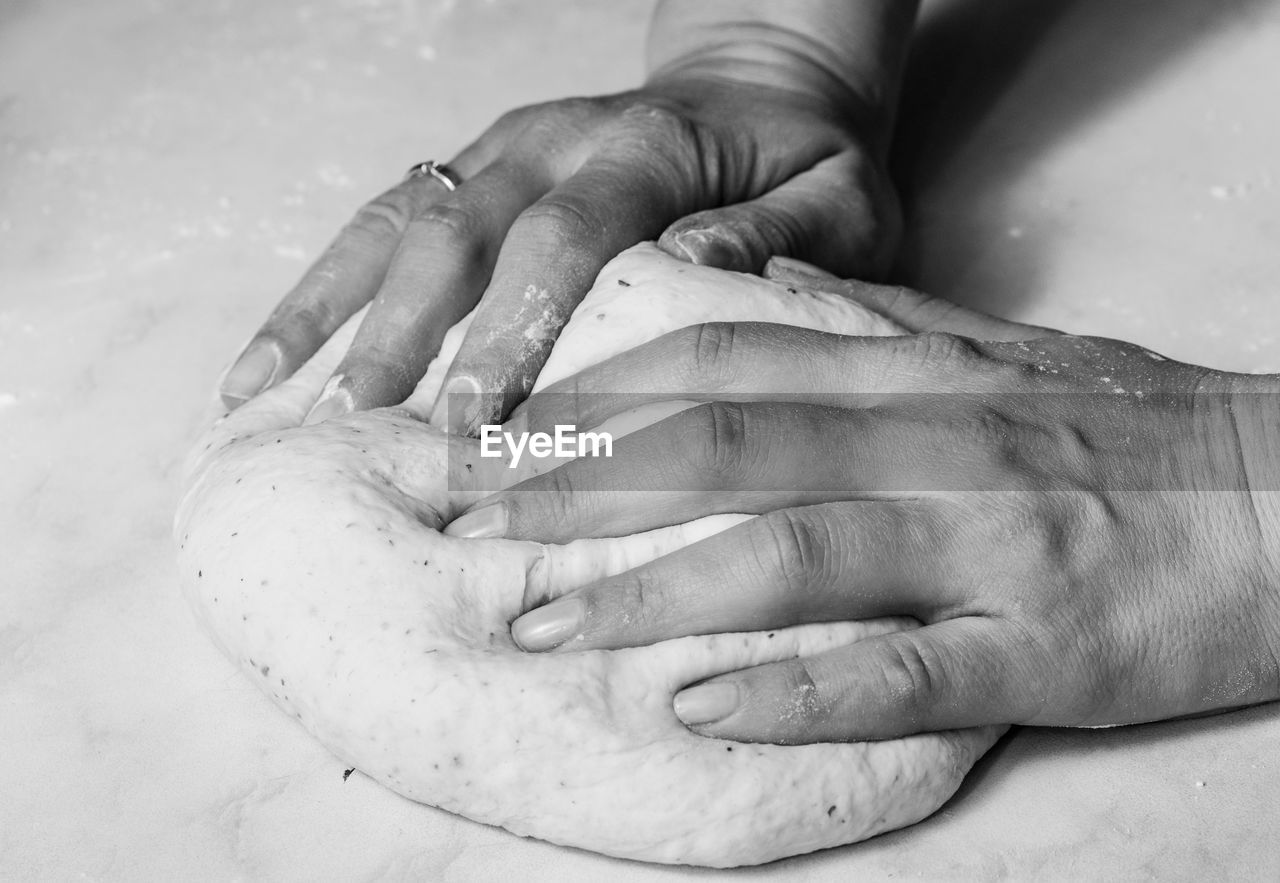 Cropped hands of person making dough on marble