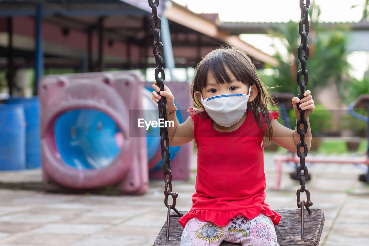 Portrait of cute girl sitting on swing in playground