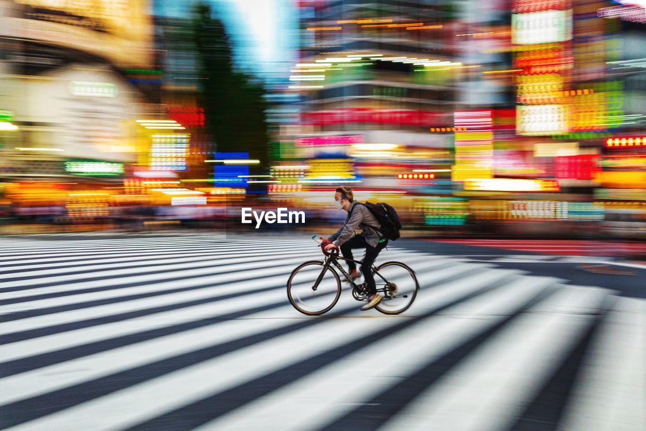 BLURRED MOTION OF MAN RIDING BICYCLE ON STREET