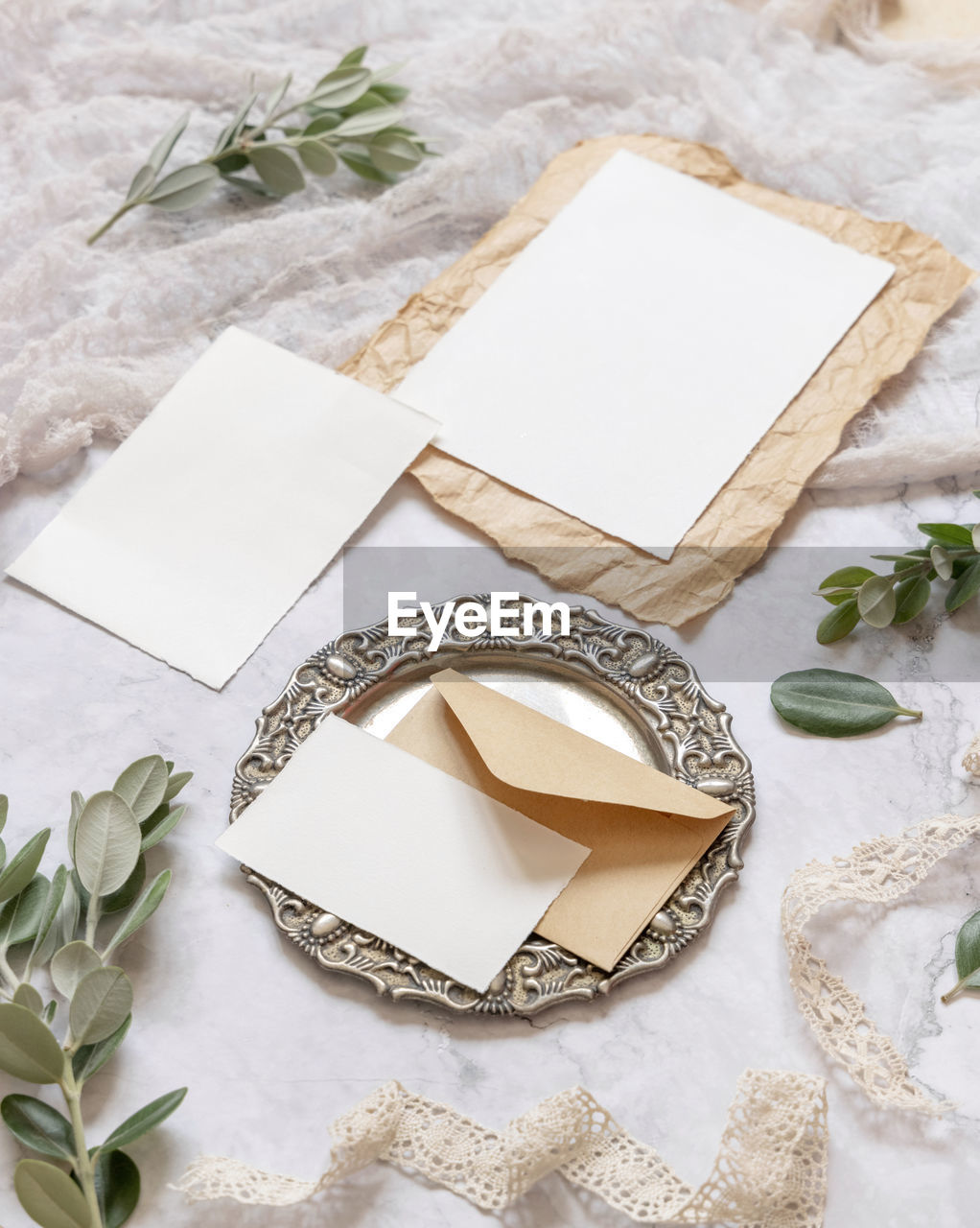 Wedding stationery set with envelope laying on a marble table decorated with eucalyptus and ribbons