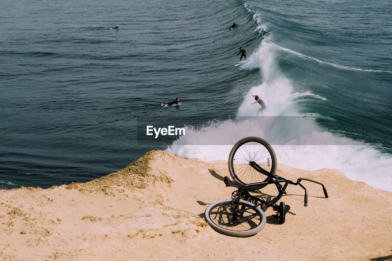 High angle view of bicycle with people surfing in sea