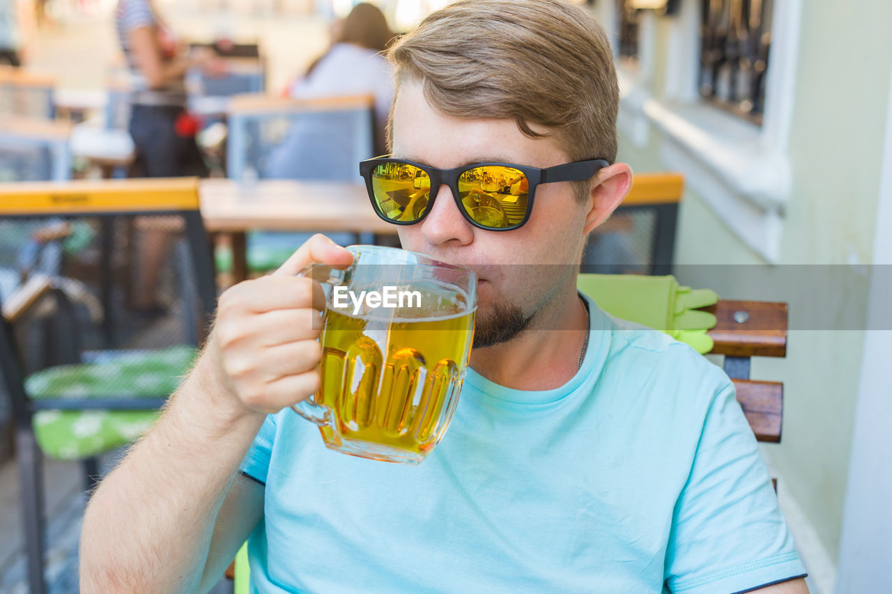 PORTRAIT OF YOUNG MAN DRINKING GLASS