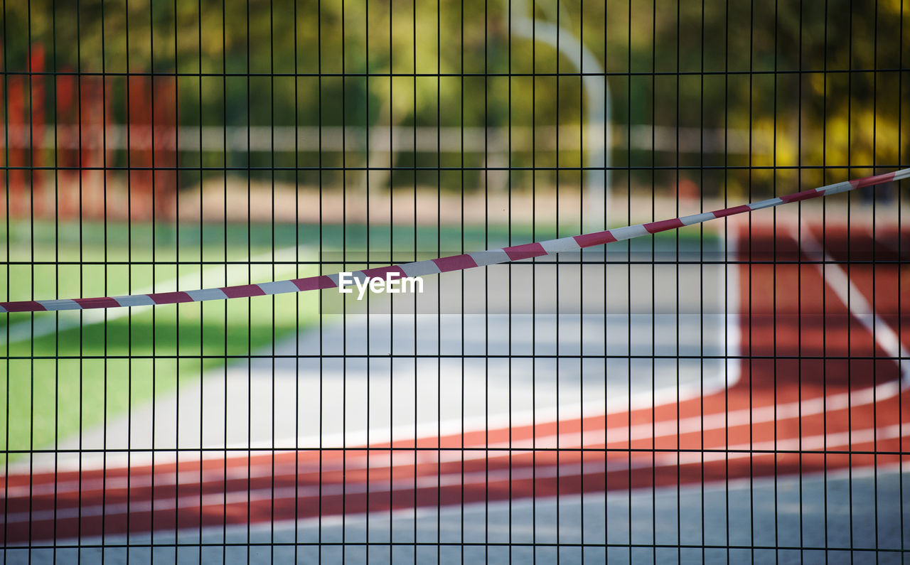 Red and white prohibitory tape on the fence of the sports complex. closed for visiting, quarantine