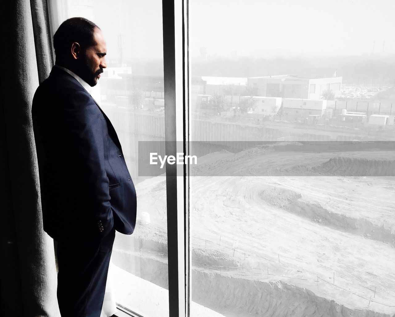 Side view of businessman looking through window in office