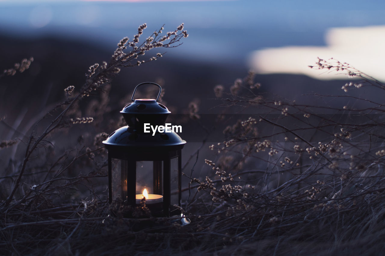 Illuminated electric lamp on field against sky